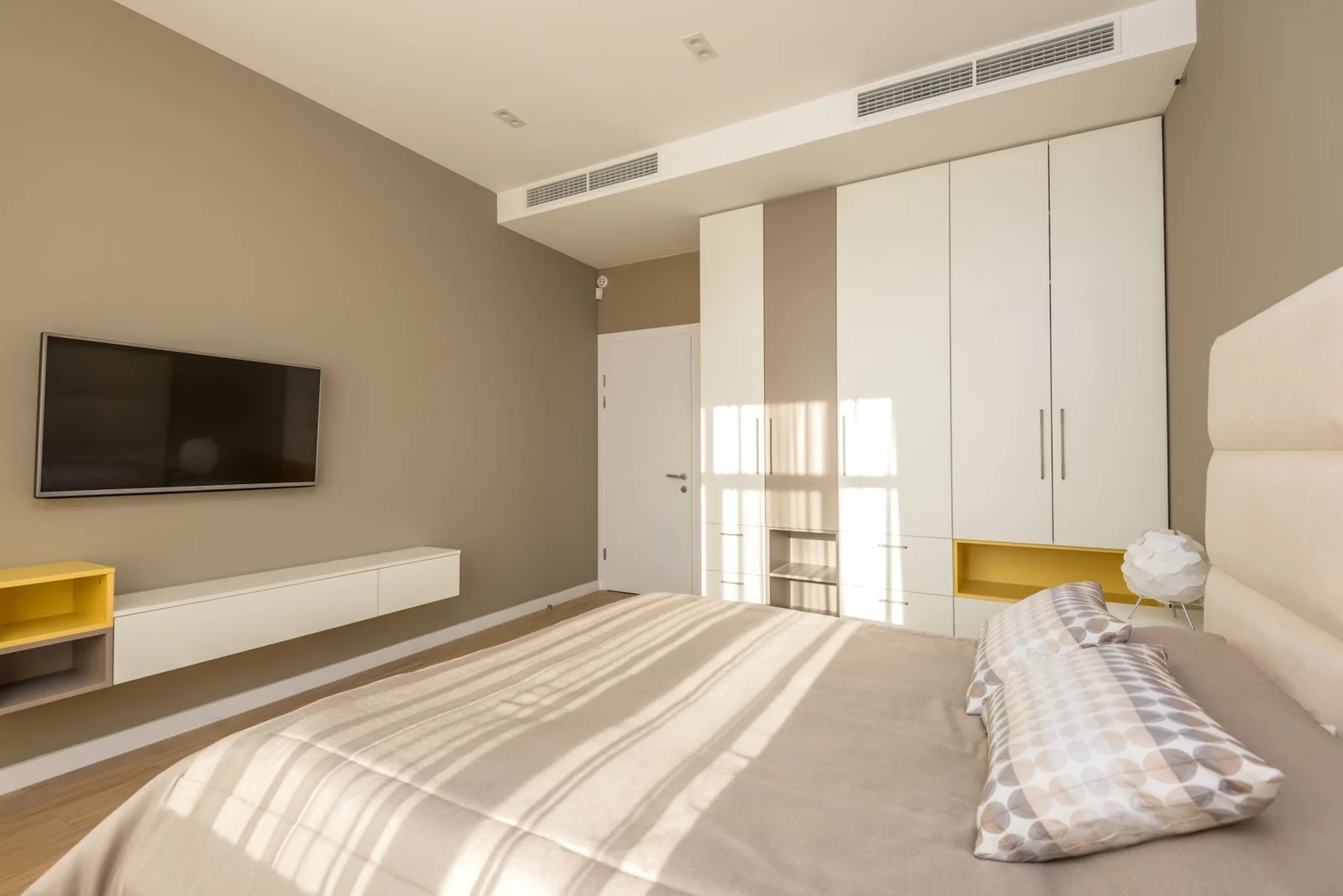 A peaceful bedroom with warm neutral colours and daylight