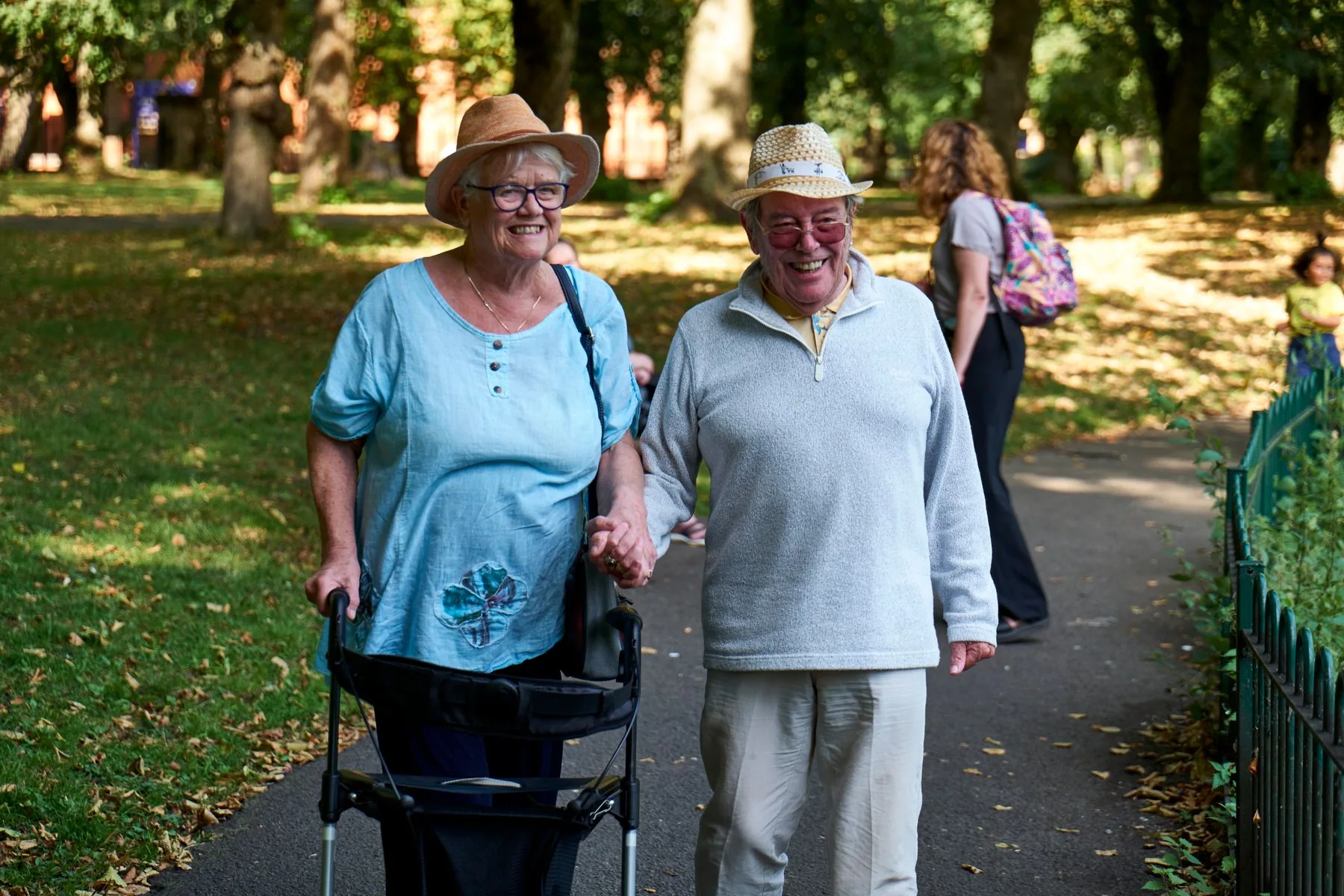 An older couple smiling and walking together in a sunny park